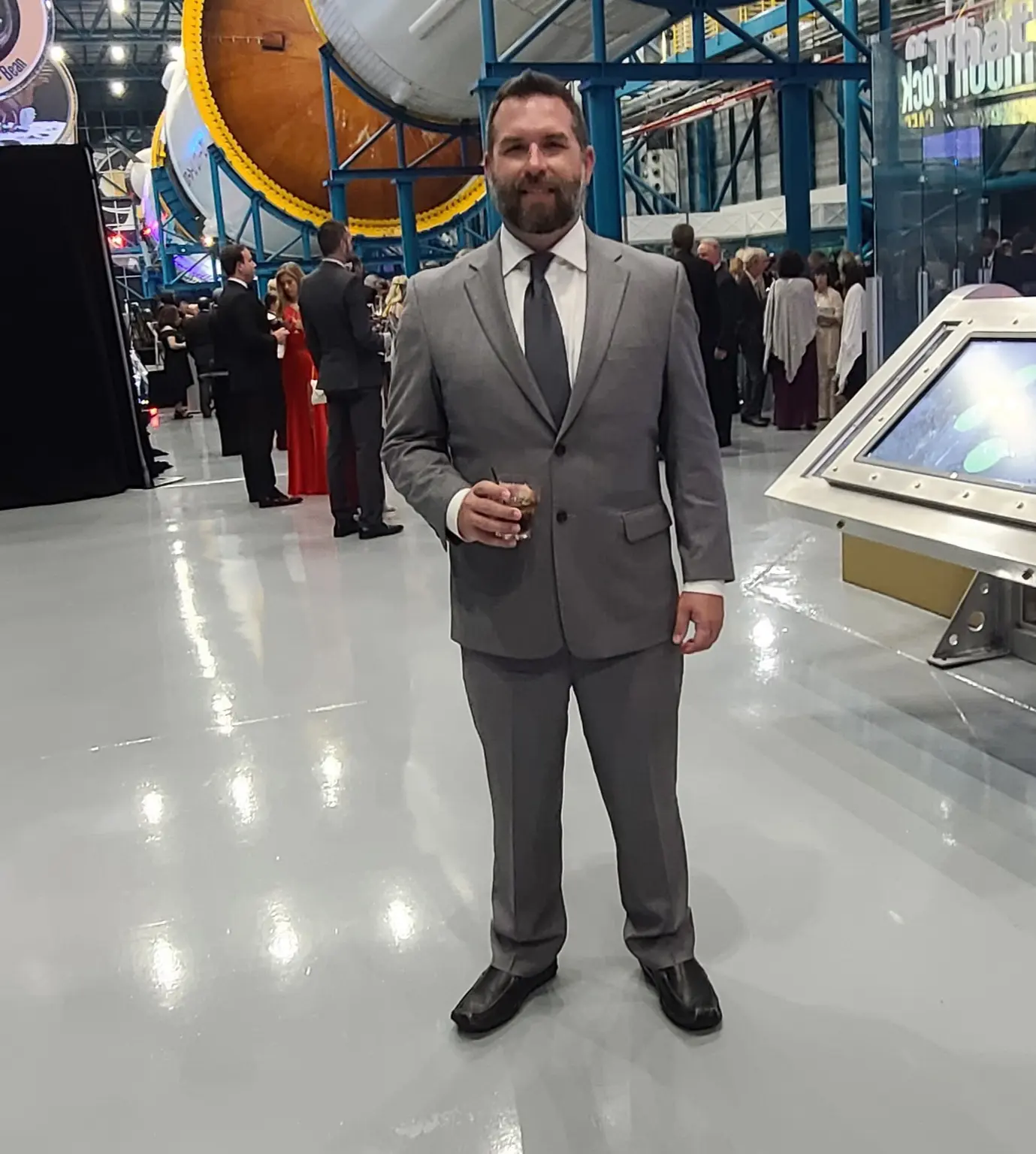 A man in a suit and tie standing next to an exhibit.