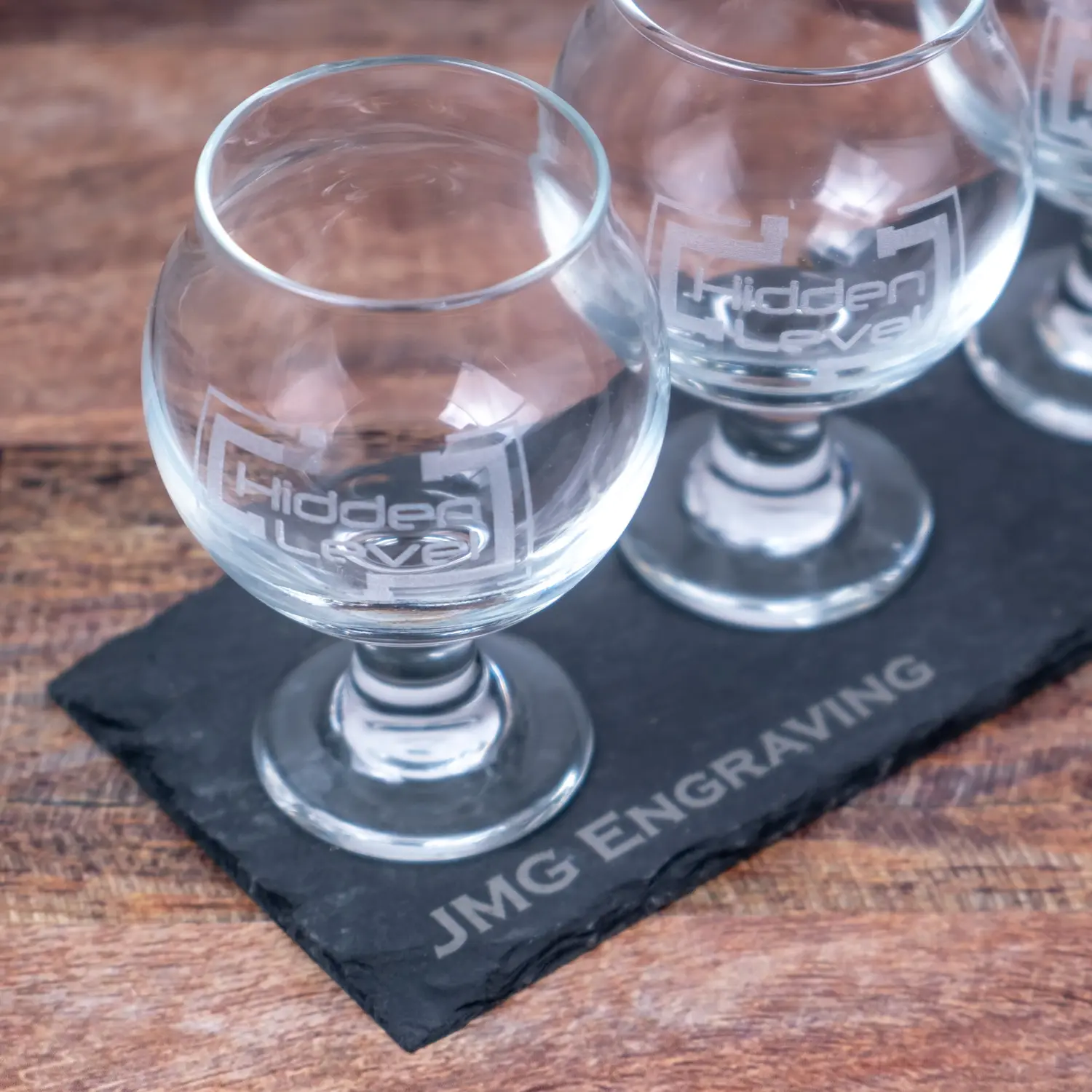 A slate tray with four glasses on top of it.