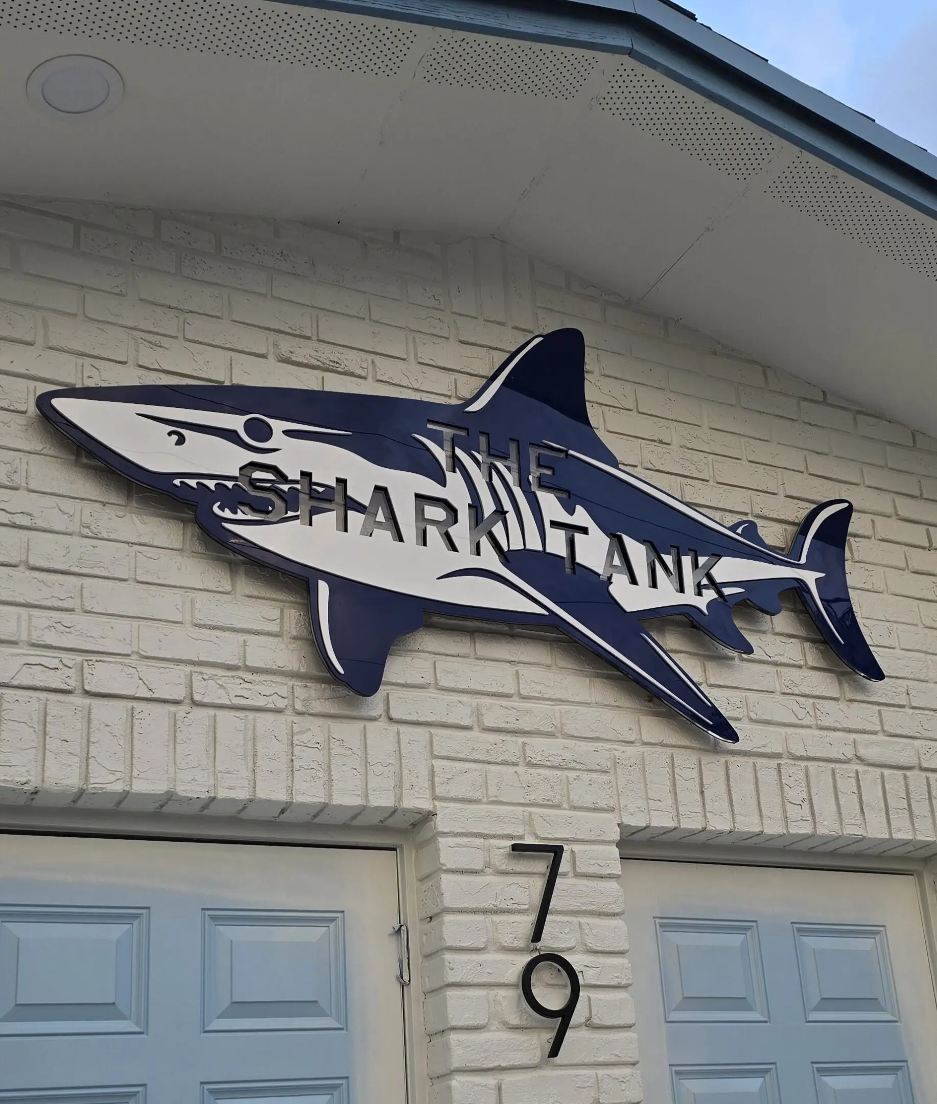 A shark tank sign hanging on the side of a building.