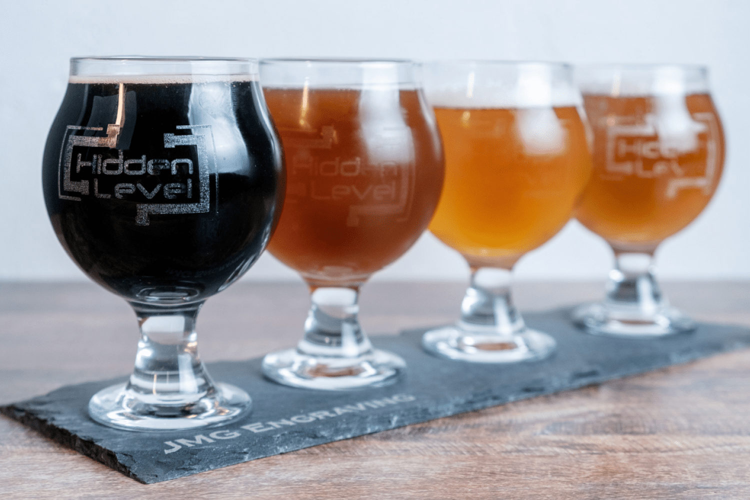 A row of different beers in glasses on a table.